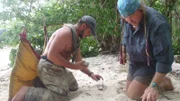 Cody Lundin and Joseph Teti work to make a fire on the beach.