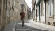 Josh Gates versucht, seine Einladung zu einem Owler-Treffen zu entziffern, während er durch die Straßen von Bourges, Frankreich, schlendert.