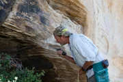 Eric Drummond looks into the cave, talking into his walkie talkie.