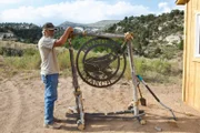 Charlie Snider leaning against Blind Frog Ranch iron sign.