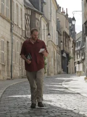 Josh Gates versucht, seine Einladung zu einem Owler-Treffen zu entziffern, während er durch die Straßen von Bourges, Frankreich, schlendert.