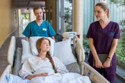Maria Köhser (Valerie Sophie Körfer, v. mit Komparse, h.) offenbart Julia Berger (Mirka Pigulla, r.) ihre privaten Probleme.