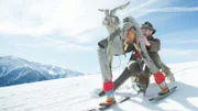 Ein Mann steigt mit einer seltsamen Statue einen schneebedeckten Berg hinab.
