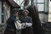 Aagnes Sampson looking down to the floor in defeat, and in the brink of tears as a man places her in the witches pyre, ready for her execution.