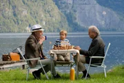 Basti Berger (Komparse, M.) schaut Arthur Jack Lowry (Georg Marin, l.) und einem Nachbar (Komparse, r.) beim Schachspielen zu.