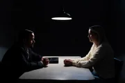 Ein Detektiv sitzt einer Frau gegenüber, gegen die ermittelt wird.