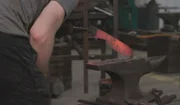 Ein Mann hält eine Klinge aus glühendem Eisen.