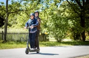 Alfons und Hildegard machen eine Spritztour mit einem E-Roller.