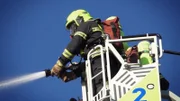 Several firefighting teams try to prevent the inferno from spreading to neighboring buildings with two turntable ladders.