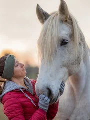 Ashley grooming a horse while the sun is setting.