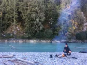 Danielle puts wood in the fire.