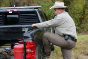 Warden Justin Eddins with his leg up on the truck’s rear tire.