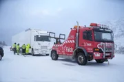 A truck lost traction on the way up a hill. Thord and his crew are helping the driver remove the chains that got stuck in his wheels and re-apply them so he can get up the hill in Haaradalen, Norway.