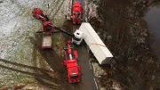 Four rescue trucks working to pull a truck and trailer.