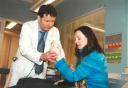 Dr. Roland Heilmann (Thomas Rühmann) bemerkt das auffällige Zittern an der Patientin (Gudrun Gabriel) und schöpft einen schlimmen Verdacht.