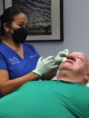Dr. Sandra Lee numbs John S. nose in preparation for surgery.