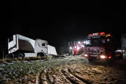 Several rescue trucks surround the trailer, getting ready to pull it back on the road.