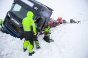 They have to dig holes in the snow next to the truck and trailer so they can get their chains around the load.