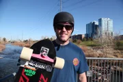 Kyle holds his skateboard outside.