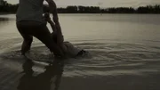 Ein Mann hält die Hände einer Frau, während sie im Wasser ist