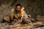 Hazen sitzt in einer Höhle und macht ein Feuer.