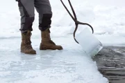 Ein Eisblock wird aus dem See gezogen während ServusTVs "Heimatleuchten - Leben im Talschluss" am Schwarzensee, Steiermark, Österreich.
