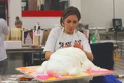 Rebecca putting white string texture on the cake.