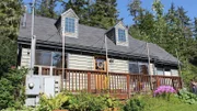 Exterior, house, at Cove House, complete with front porch, grey siding, surrounded by trees, near Juneau, Alaska, as seen on Great American Country's Living Alaska