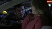 Ein Mann lächelt eine Frau an, die in einem Auto sitzt