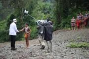 Crew members film handshake between Morgan Freeman and his Embera village guide, Nelson Mepaquito, while other tribe members stand by.