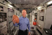 Former commander of the International Space Station, Tim Kopra, holds a football.