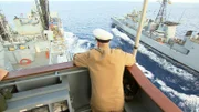 Der Kapitän des Schiffes lehnt an der Reling und beobachtet das Schiff.