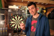 Mark Rober poses with his automatic bullseye dartboard.