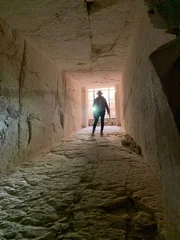 Ramy Romany walking down tomb hallway.