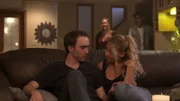 Ein Mann und ein Mädchen sitzen auf einer Couch, während eine Frau und ein Mann hinter ihnen zusehen.