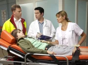 Nico Kress (Friedrich Heine, 2.v.li.) vom Notarzt (Komparse, li.) mit Bauchschmerzen in die Sachsenklinik eingeliefert. Schwester Yvonne (Maren Gilzer, re.) erkennt ihn wieder und berichtet Dr. Philipp Brentano (Thomas Koch, 2.v.re.) von Nicos Befund des Vortages.