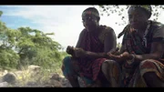 Two hadzabe enjoying a meal by the fire.