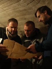 Sebastian Terenada () und Oliver Kruger (r.) zeigen Josh Gates (l.) eine Karte des Nazitunnels.
