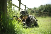 RE-CREATION - Von Kron crawls through the grass with a rifle. He is one of the SS soldiers who was involved in the Le Paradis Massacre.