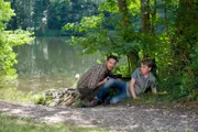 Die Krokodiljäger Vinzenz Grieshaber (Michael Sideris) und Pawel (Moritz Knapp) liegen an der Uferböschung auf der Lauer. Derweil ist auch Großwildjäger Roy Freitag unterwegs.