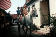 Auf dem Pferd "Kleiner Onkel" reitet Pippi, Tommy und Annika durch ihre kleine Heimatstadt.