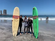 Iquique, Chile. Ausflug Surfen: Günther und Lara am Stadtstrand von Iquique. Sie treffen auf Guide Jonas von Escondida/Ecosurf. Der Guide macht mit ihnen nur ein paar ganz kurze Trockenübungen am Strand und dann geht es ab ins kalte Wasser.