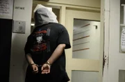 Sacramento, California: A new inmate in handcuffs with a spit mask to protect deputies from being split on while they are checked in.