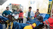 Arnulf Emmerling (Christofer von Beau, 2.v.r.) und Lukas Petersen (Jean-Luc Caputo, 2.v.l.) werden nach einem Hausbrand in die Notaufnahme des Johannes-Thal-Klinikum eingeliefert. Mikko Rantala (Luan Gummich, l.) und Ben Ahlbeck (Philipp Danne, M.) übernehmen die Patienten von den Rettungsanitäter:innen (Kompars:innen).