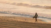 Einmal Sonne tanken. Wir sind unterwegs zu den schönsten Stränden der Welt. Von der Algarve bis zu den Seychellen - 20 Traumstrände, die Sie kennen sollten. - Surfer vor der Brandung.