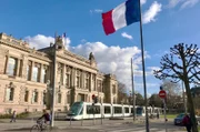 Eine Straßenbahn, hier ein Citadis Triebwagen, hält am Place de la République, vor dem Staatstheater.