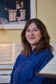 Eva Mattes im Portrait vor dem Klavier.