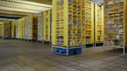Blick in ein KI-unterstütztes Logistikzentrum von Amazon: Transportroboter bringen die Regale mit der benötigten Ware zu den Packern.