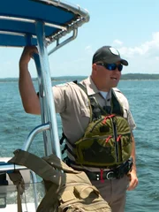 Warden Inman hanging off a boat