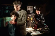 George (Jemima Rooper, l.) und Quentin (Christopher Good, M.) werden als Geiseln gehalten. Johnson (Patrick Fields, r.), einer der Verbrecher, versucht von Quentin dessen Forschungsergebnisse zu erpressen.